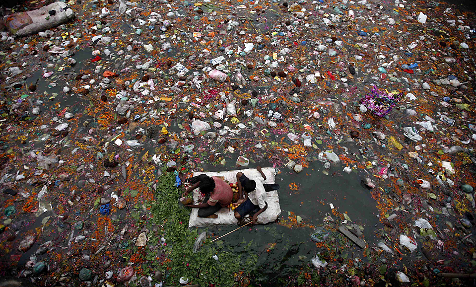Fishermen search for offerings thrown in by worshippers in the polluted waters of the river Sabarmati in Ahmedabad